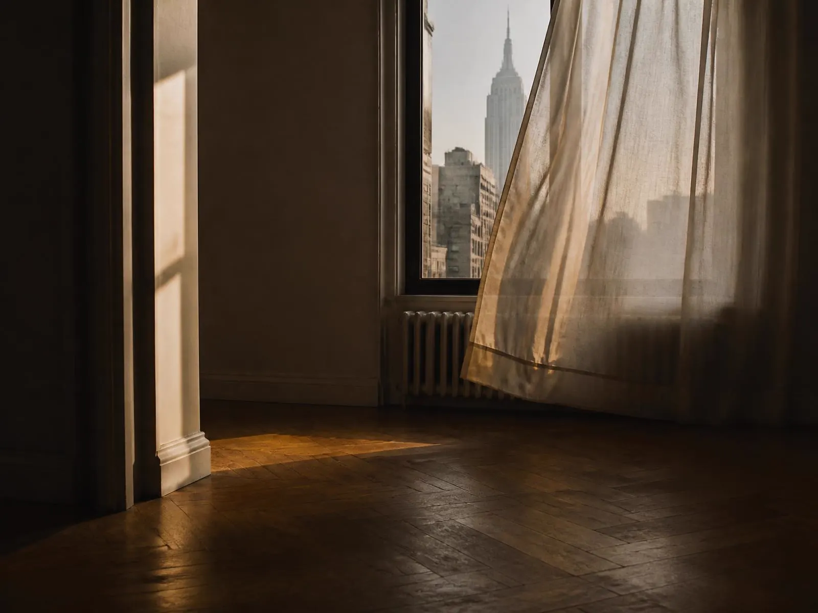 Quiet Manhattan interior with sheer curtain moving in late afternoon light